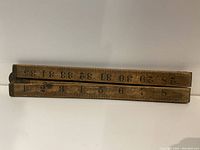 Closed view of the wooden fold-up measuring stick showing the numbers 1 through 35 in black on wood.