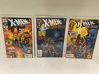 Front view of three X-Men True Friends comic books standing upright, showing full cover art.