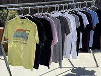 Lot of 15 assorted graphic T-shirts on hangers outdoors showing front designs and colors