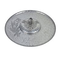 Angled view of the round hammered aluminum tray showing the embossed floral pattern and raised flower motif in the center.