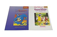 Two vintage Disney songbooks with colorful covers, Aladdin (purple cover) and Snow White (white cover)