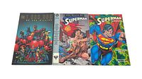 Three Superman TPB comic books laid side by side: '1,000,000', 'The Death of Superman', and 'Superman: Birthright'.