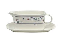 Photo of Mikasa Intaglio Annette gravy boat with matching dish, showing side view of handle and floral vine pattern.