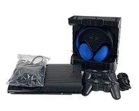 PlayStation 3 Slim console with cables in plastic bag, two controllers, and headset.