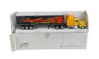 Full view of Kenworth semi truck and trailer set in original white box with damage and wear, showing yellow cab and black trailer with flames and Kenworth branding.