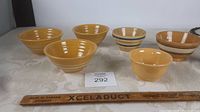 Six yellow ware bowls of varied sizes and stripe designs, displayed from front