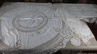 Round tablecloth displayed flat with visible crocheted lace border and circular central design.