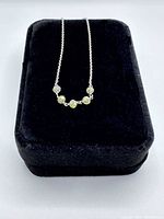 Necklace with five faceted blue-green diamond beads displayed on black velvet box