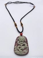 Full view of the jade dragon pendant on the black braided adjustable rope necklace.