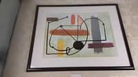 Full view of framed Joan Miró abstract art print showing geometric and organic shapes with colorful blocks under glass.