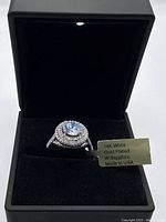 Ring displayed upright in black velvet-lined box with LED light visible at top