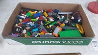 Box containing assorted Lego bricks in multiple colors and shapes.