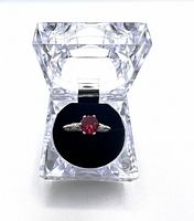 Full view of the ruby ring displayed inside a clear acrylic box with black velvet insert.