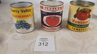 Front view of three vintage cans: Cherry Valley Blueberries, Barbara B Tomatoes, and Mowbray's Tomatoes with a MaxSold lot number card
