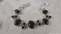 Full view of bracelet showing polished oval blue tiger's eye stones and pairs of smaller faceted topaz stones set in sterling silver.