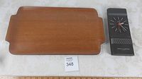 Teak serving tray with side handles next to the Marlet's Slagerijen Germany wall clock on a light surface