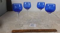 Set of four vintage cobalt blue wine glasses with hand twisted clear stems, standing on a table