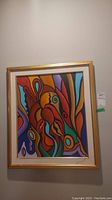 Full view of framed abstract art painting with colorful, flowing shapes and gold frame.
