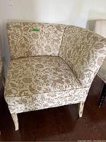 Front angle view of fabric cushioned chair with floral pattern upholstery and wood legs.