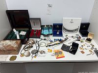 Full spread of jewelry, watches, and boxes on white table showing wide variety and quantity