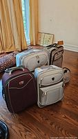 Overview of five luggage bags arranged on hardwood floor showing color and size differences