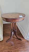 Full view of round side table on wood floor next to upholstered seating
