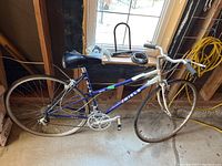Full side view of Miele Binova 19 inch road bicycle with white and blue frame, black saddle, worn tires, and drop handlebars with brake levers.