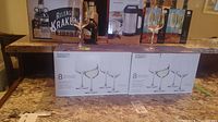 Two unopened boxes of Mikasa Gianna white wine glasses, each box contains 8 glasses shown on the countertop.