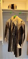 Coat on green hanger with matching hat on shelf
