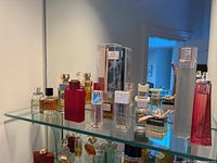 Overview of ten assorted glass perfume bottles on a glass shelf with mirrored background