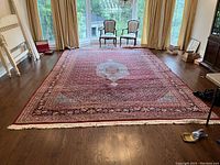 Full room view of red wool rug laid flat on hardwood floor