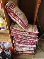 Stack of eight DynaMatrix brown polymeric sand bags on shelving