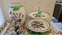 Photo showing the 9.5 inch Portmeirion Botanic Garden vase and the two-tier tidbit tray side-by-side on a granite countertop.