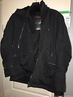 Front view of black Prada ski jacket showing zippered pockets, D-ring, and Avalanche Technology label inside
