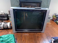 Front view of the Sony Trinitron CRT TV showing the screen, casing, and remote control on top