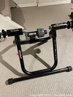Photo showing full Blackburn black metal track stand with labels and mounting points for bicycle.