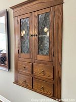 Full view of built-in bar cabinet with two glass paneled doors and four drawers below.