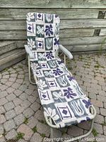 Full view of one folding lounge chair outdoors on patio with floral and geometric fabric upholstery.