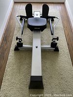 Top-down front view of the rowing machine showing footrests, seat, and hydraulic arms.