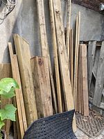 Wood boards leaning against wall, showing assorted sizes and some weathering.
