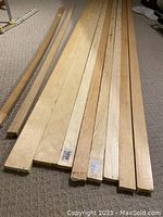 Nine wood pieces laid out on a carpeted floor showing six 1x2 strapping pieces, two 1x4 pieces, and one Douglas fir board.