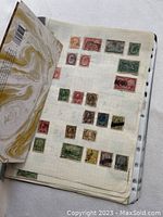 Photo showing wide assortment of older Canadian postage stamps on album page, including brown, red, green, and muted colors, mostly used.
