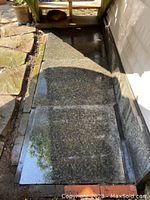 Three large polished granite-like slabs arranged side by side outdoors, showing rectangular shape and speckled grey-green color.
