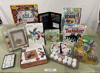 Wide view showing all items in the lot including finger painting kit, markers, pinwheel kit, Twister game, chalk, blocks and dominoes.