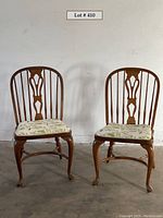 Two hardwood chairs side by side, showing front and backrest design with fabric seats