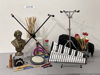 Photo showing the percussion instruments laid out including Glockenspiel bell kit, stand, drum pad, maracas, drumsticks, metronome, bust of Wagner, and children's percussion items.