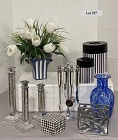 Full view of lot: silk white tulips in striped vase, two striped metal canisters, blue art glass vase, set of Towle mother of pearl candle sticks, small herringbone box, and metal napkin holder