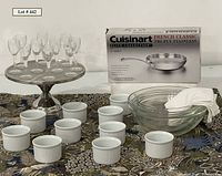 Full lot display showing metal pedestal with 10 aperitif glasses, 10 white porcelain souffle cups, 3 clear glass mixing bowls, Cuisinart skillet box, and white flour sack towels.