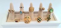 Front view of 10 vintage cocktail rings on individual presentation cones showing various colored stones and gold-tone bands.