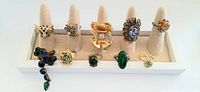 Front view of all 10 vintage cocktail rings displayed on a fabric padded ring holder, showing full ring designs and colors.